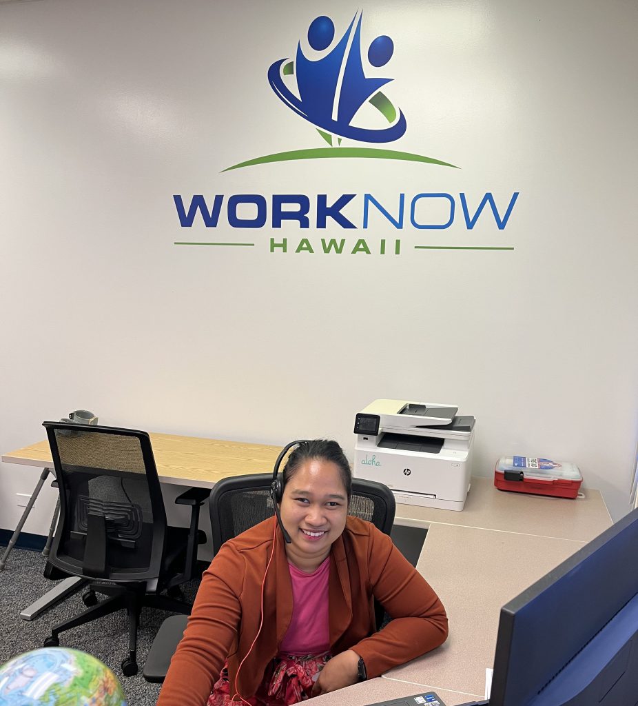 Kristine smiling at her office desk, under the WorkNow Hawaii logo