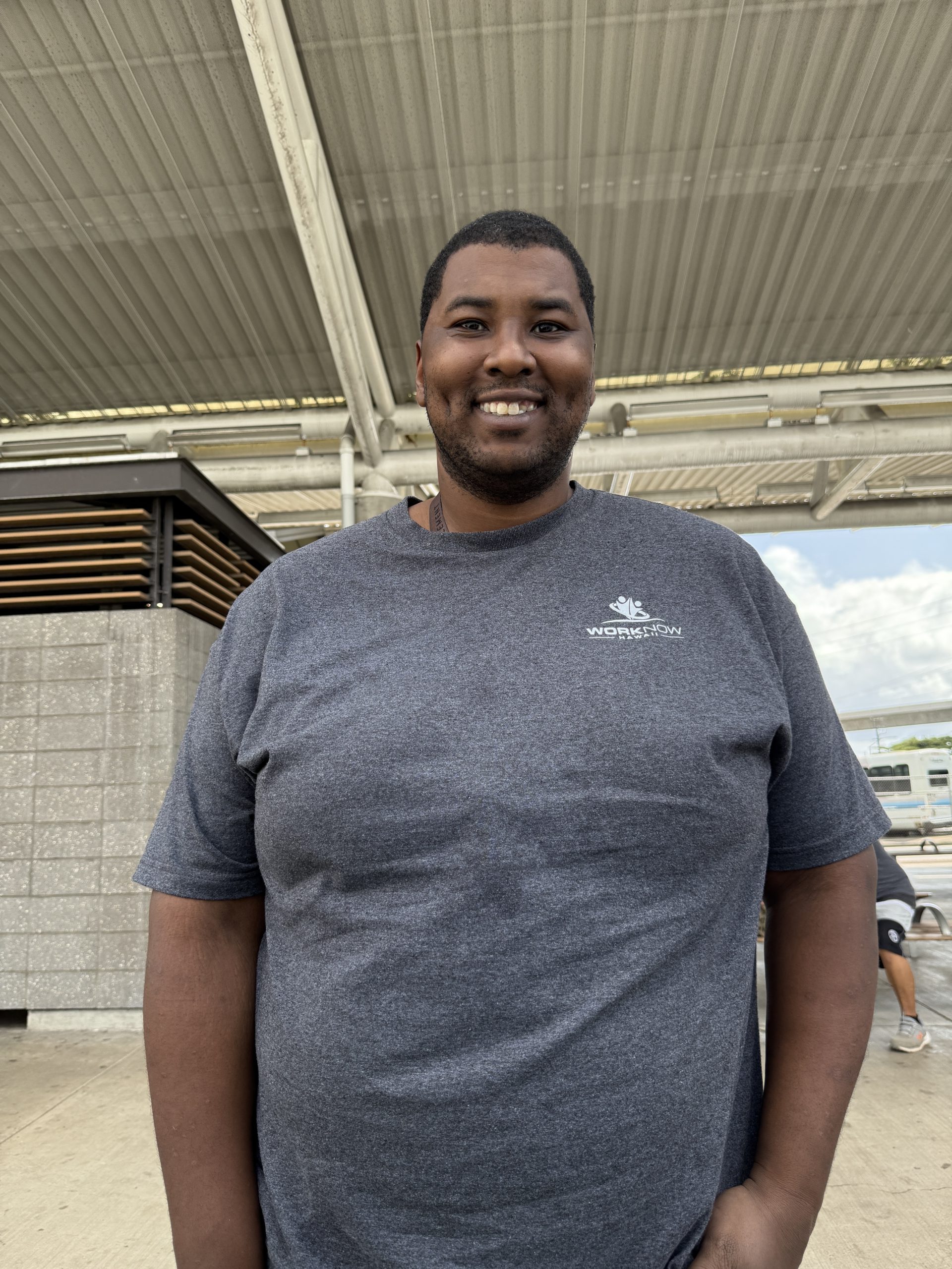 Image of Christopher standing in his Work Now Hawaii T-shirt.
