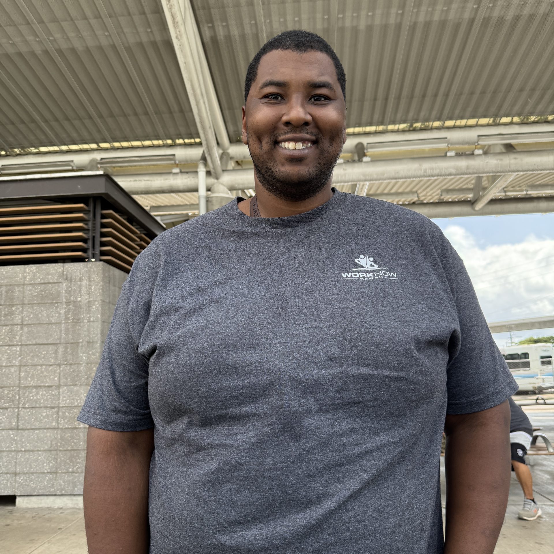 Image of Christopher standing in his Work Now Hawaii T-shirt.