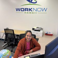 Kristine smiling at her office desk, under the WorkNow Hawaii logo